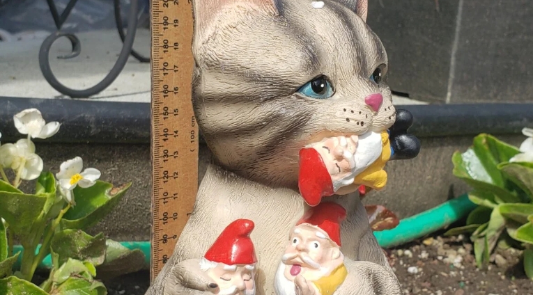 cat eating gnomes statue